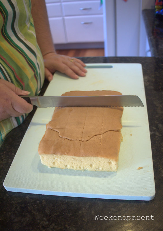 My friend carefully cutting the sponge cake into even squares